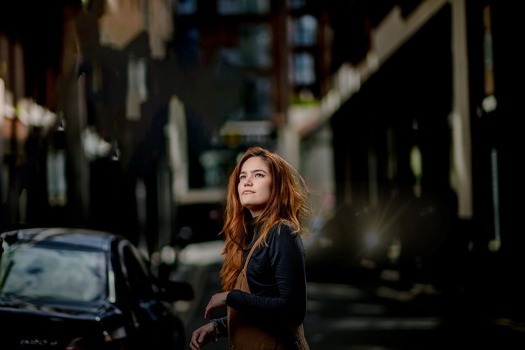 A woman with red hair gazes up while walking in the street in a black shirt after some act prep in des moines