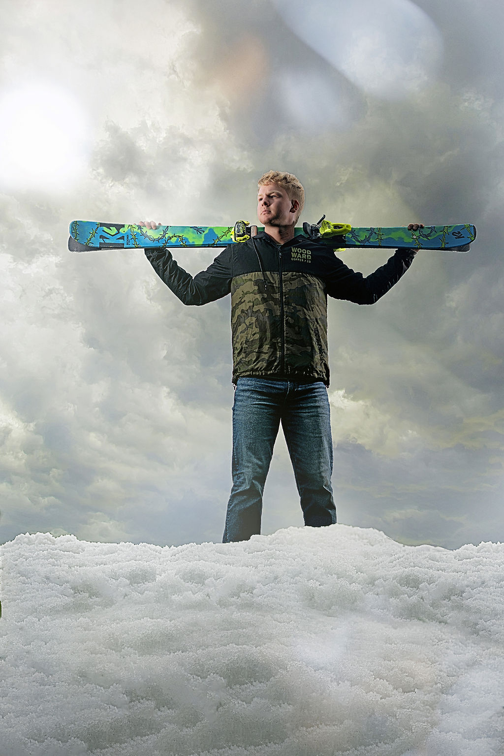 A roosevelt high school des moines stands on a pile of snow with skis over his shoulders