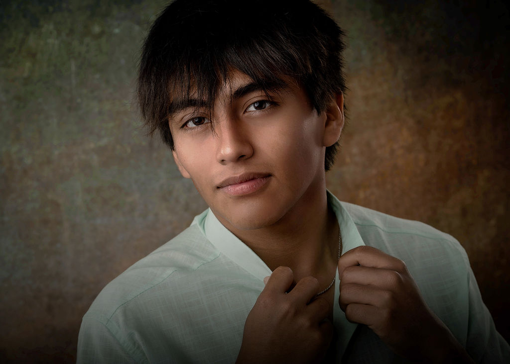 A close up of a high school senior with dark hair in a white shirt with hands on his collar after finding tux rental in Des Moines