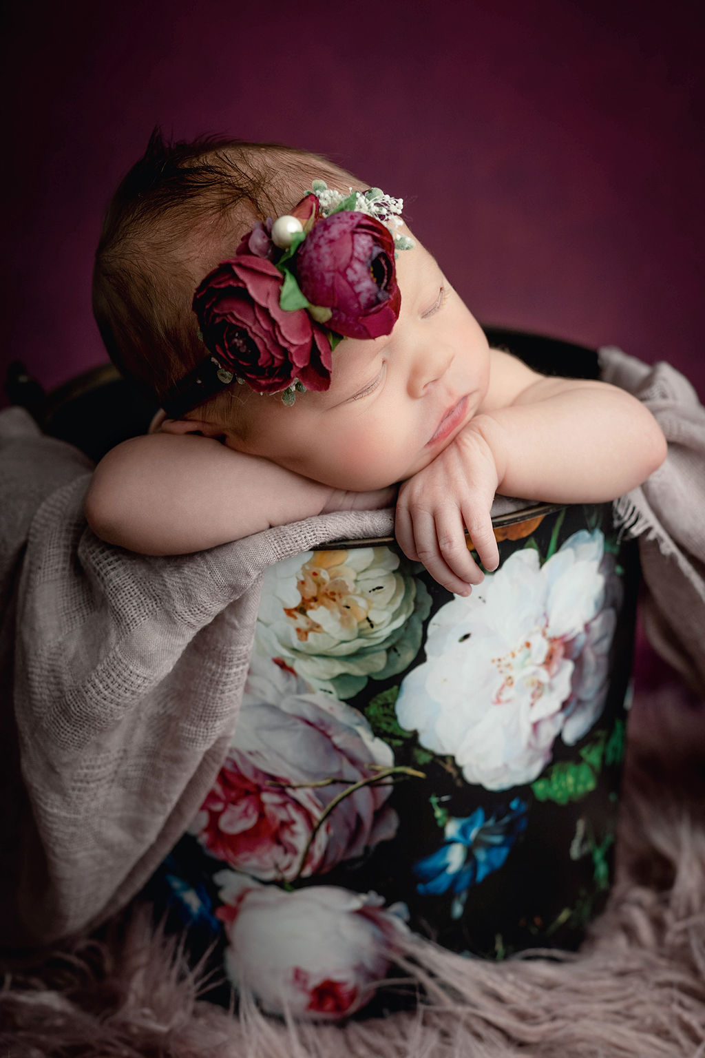 A newborn baby sleeps in a floral metal bucket with a matching headband after visiting a baby boutique in des moines