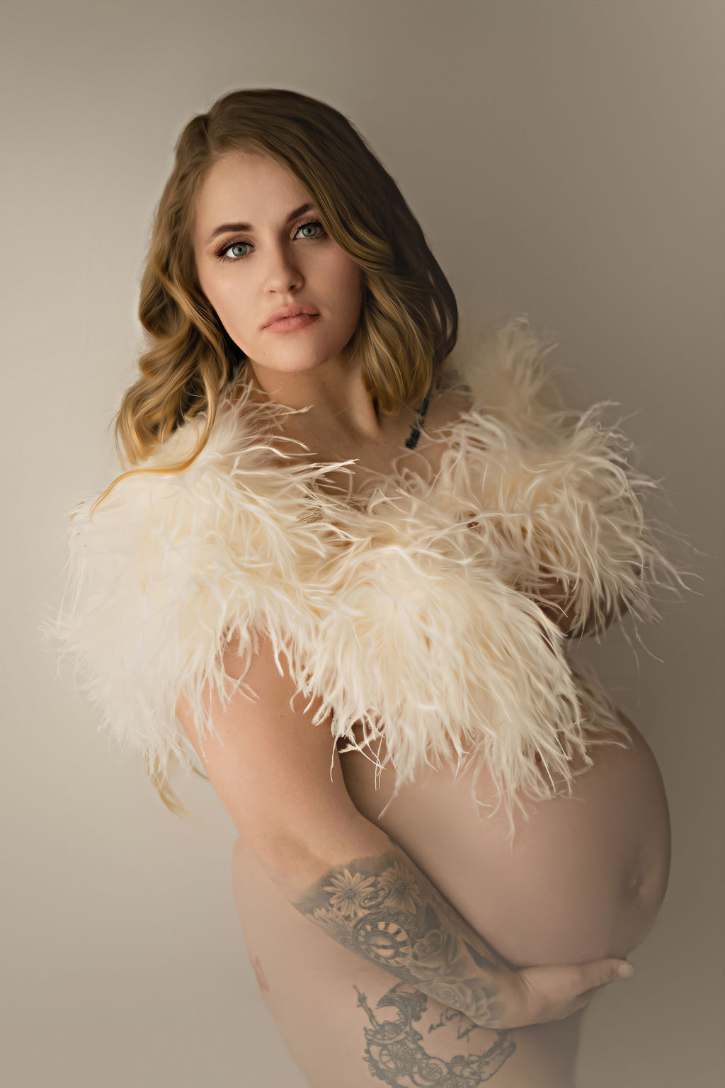 A pregnant woman covers her chest with a white feather boa with a hand under her bump in a studio after visiting family birthing center pella