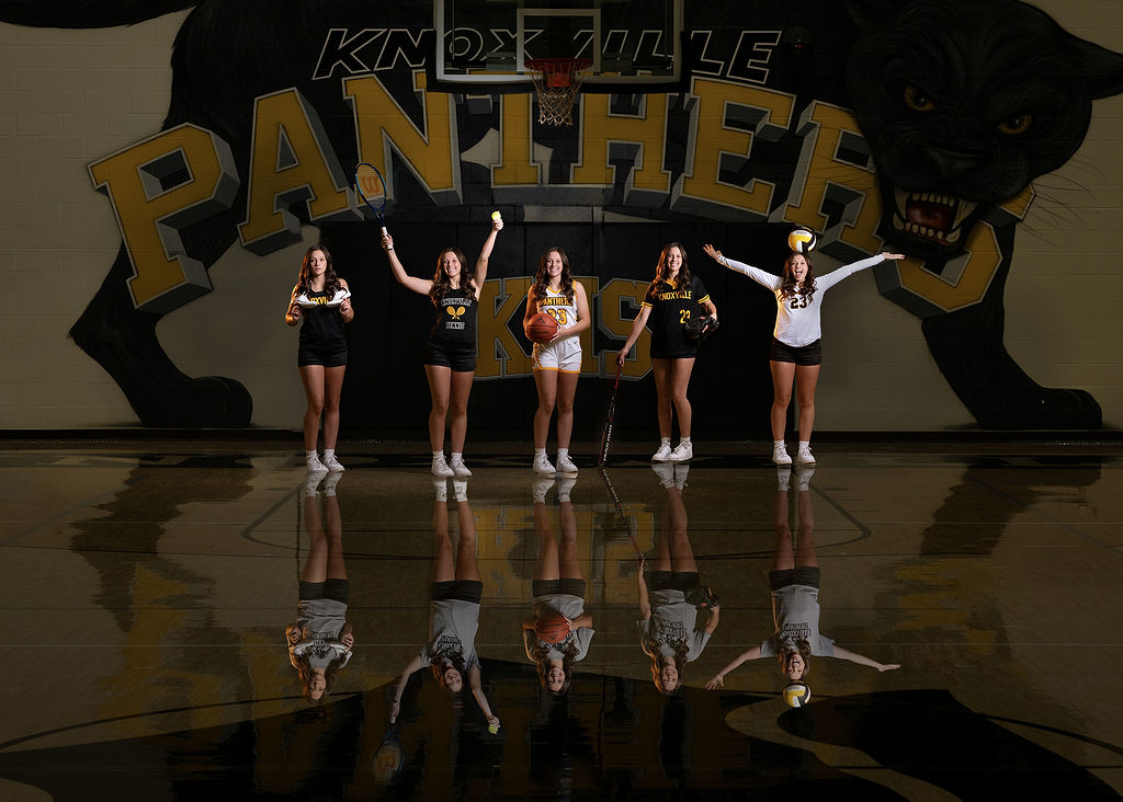 5 knoxville high school iowa girls sports players play with their assorted sports tools in the gym by the logo