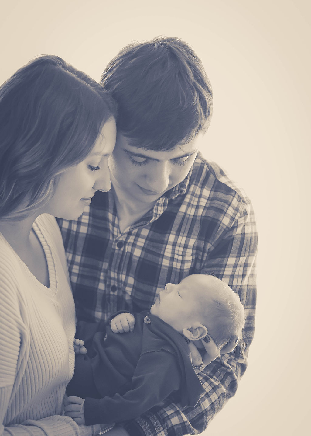 Happy new parents smile down at their sleeping newborn in their hands after some parenting classes in des moines