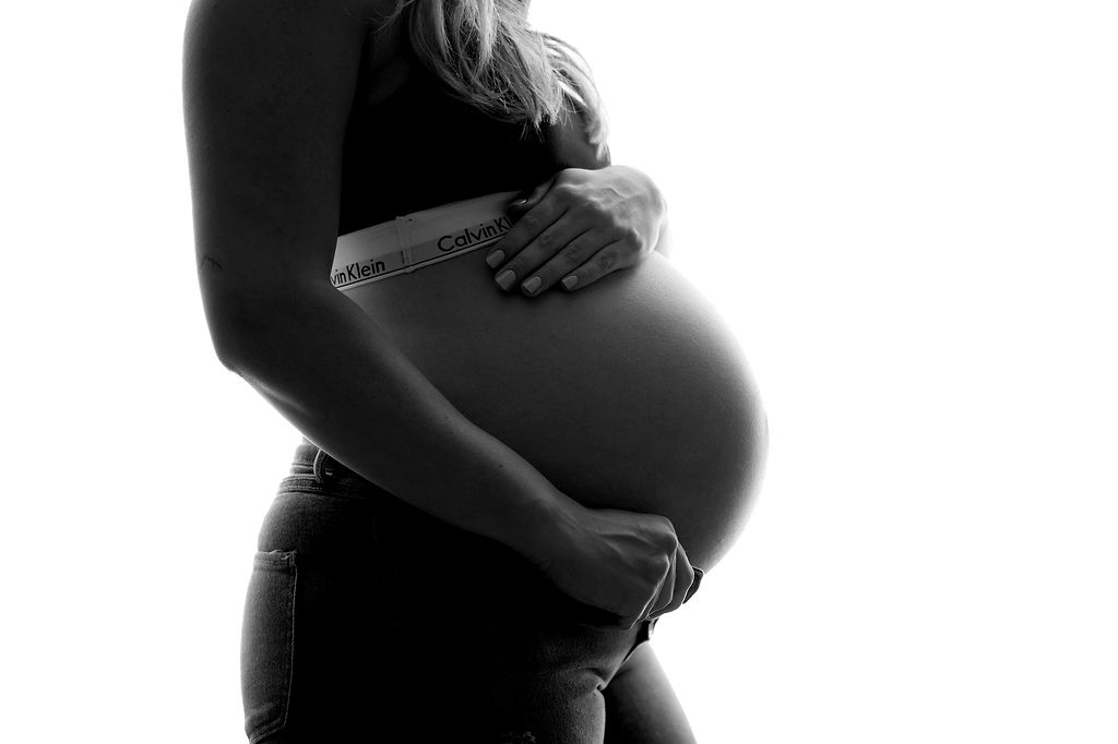 Details of a mom to be's bump while standing in a studio