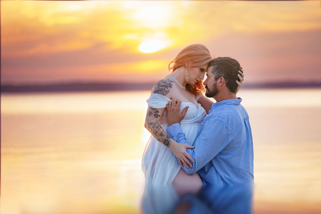 An expecting couple shares an intimate moment in the water on a beach at sunset after some prenatal yoga in des moines