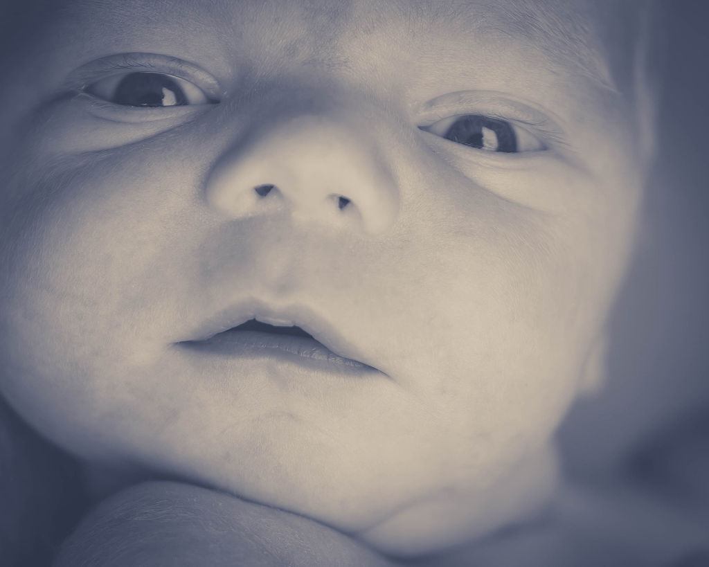 Close up details in black and white of a newborn baby's face with open eyes before visiting tongue tie center of iowa